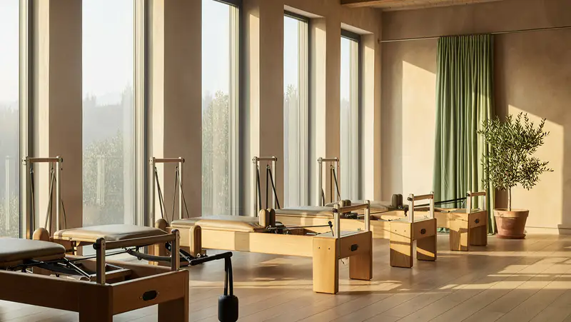 An empty reformer pilates room at sunrise, light through tall windows